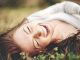 Una mujer tirada en el parque riendo a carcajadas y aprovechando los beneficios de la risa