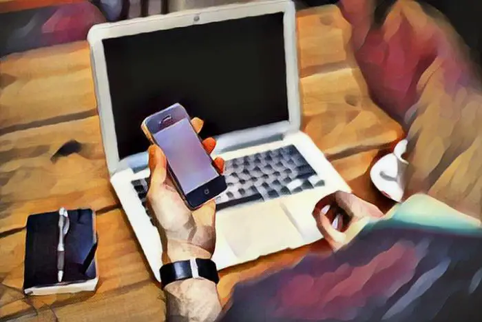 Hombre utilizando celular y laptop por addición al internet