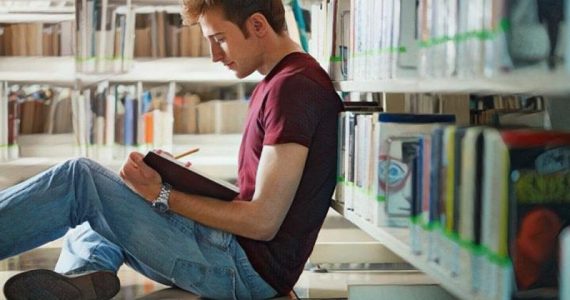 Persona joven introvertida en la biblioteca leyendo un libro