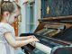 Niña tocando el piano desarrollando su inteligencia musical